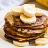 close up of a stack of banana pancakes topped with sliced bananas and syrup