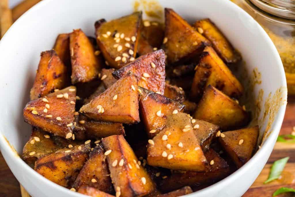 close up of white bowl with triangles of cooked air fryer tofu inside, topped with sesame seeds