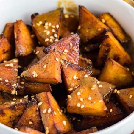 close up of white bowl with triangles of cooked air fryer tofu inside, topped with sesame seeds