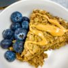 bowl of amish baked oatmeal with blueberries on the side and peanut butter on top