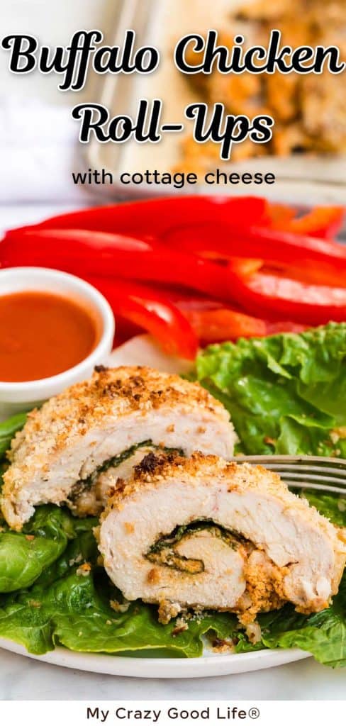 close up of cooked buffalo chicken roll up on a bed of lettuce on white plate. Small bowl of buffalo cause and sliced red peppers in the background. 