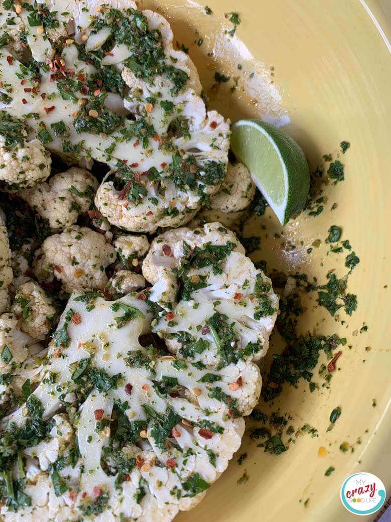 top down view of raw cauliflower steaks in a yellow bowl