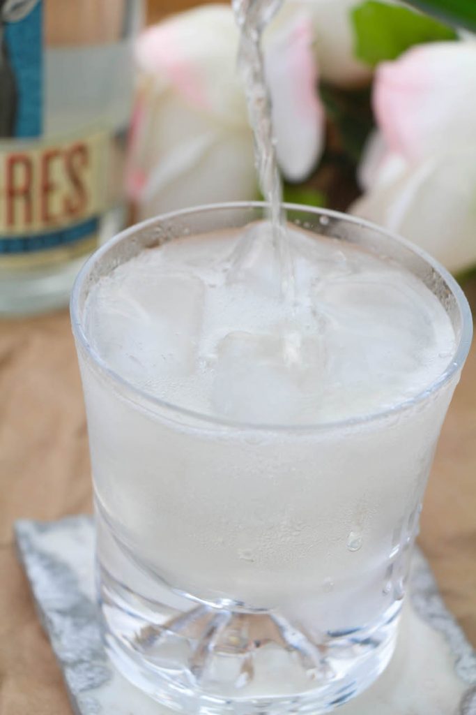 Champagne margaritas being poured into a gorgeous glass with a beautiful marble coaster. 