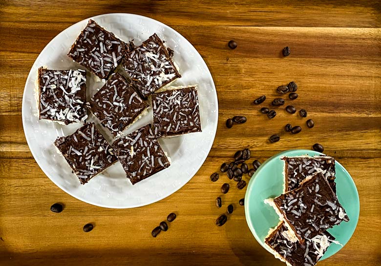 coconut bars on white plate with coffee beans