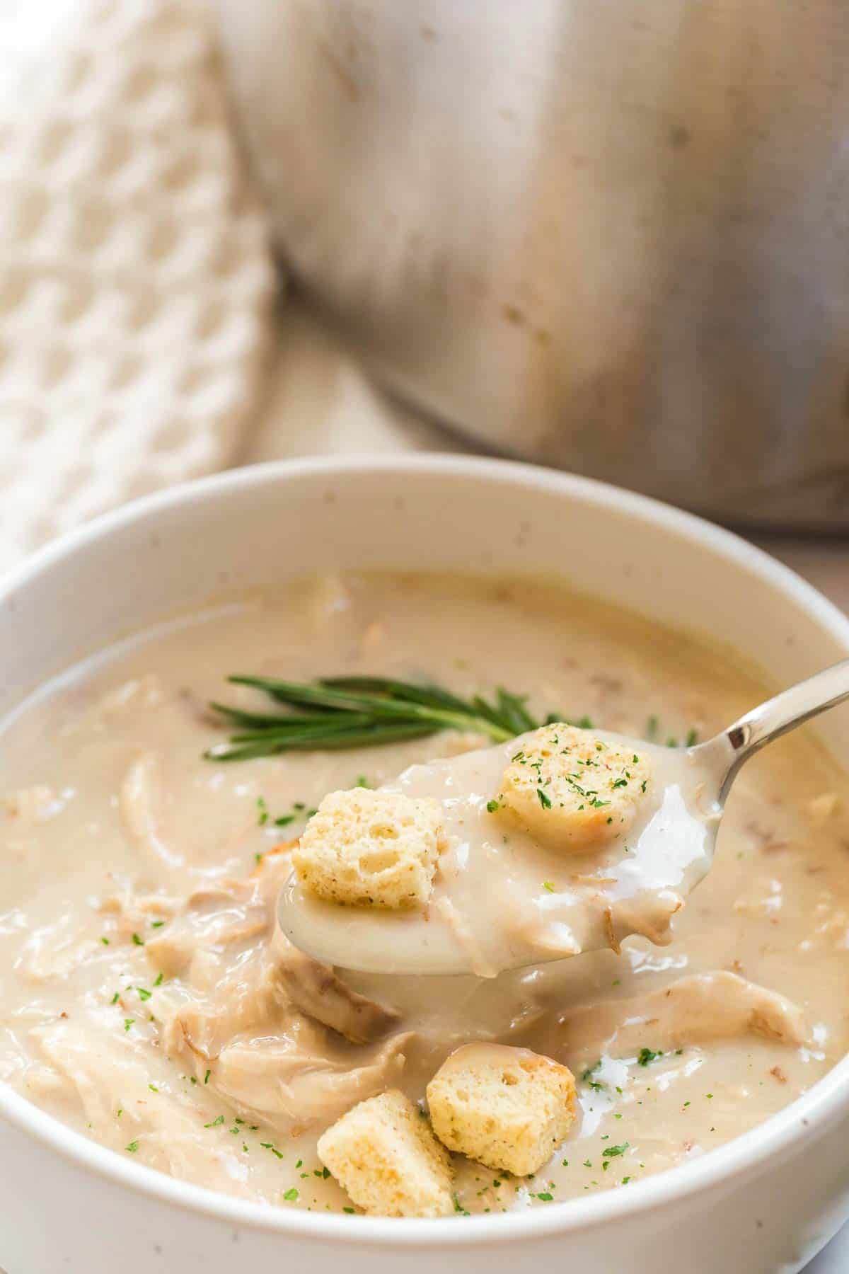 close up of white bowl of soup with croutons and herbs