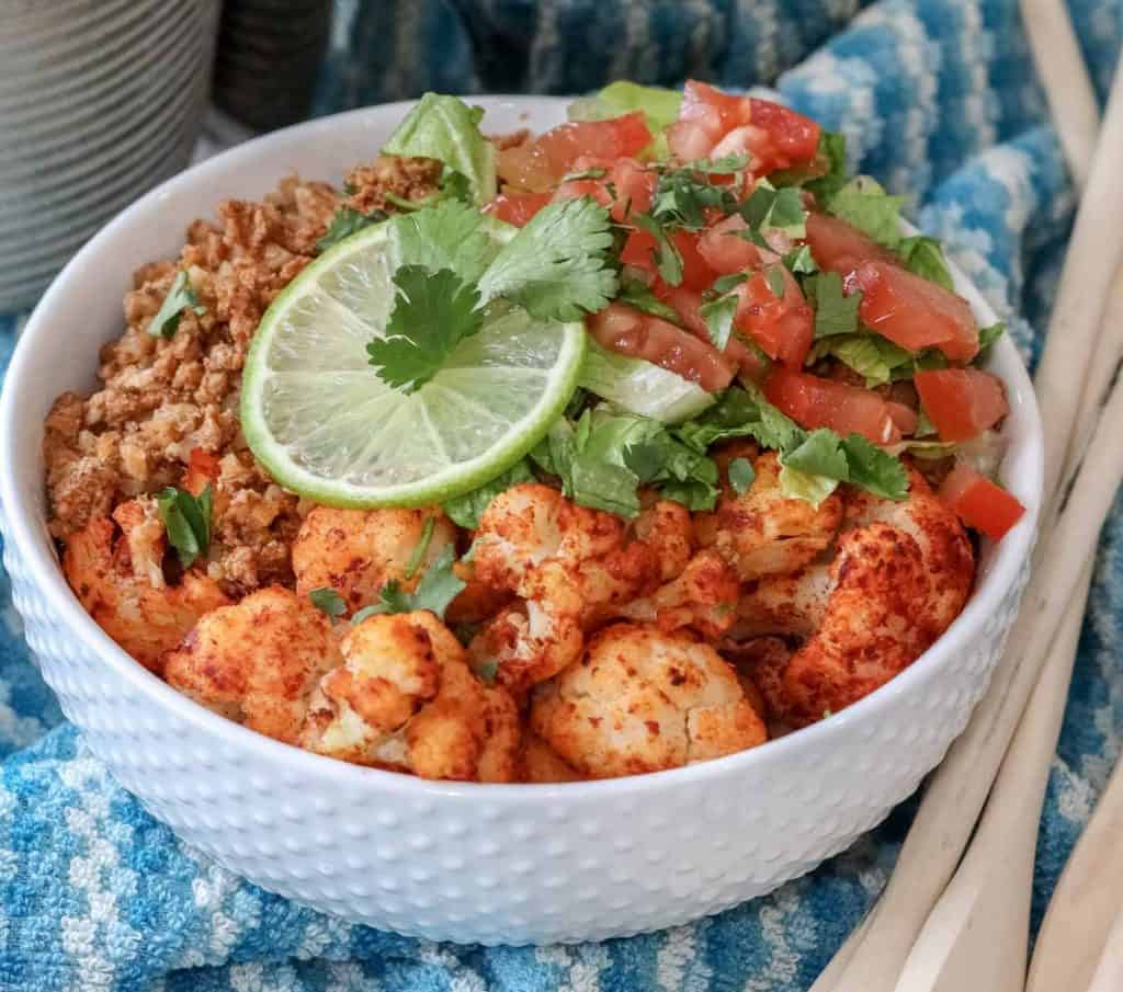 close up of frozen cauliflower and prepped taco meat in a white bowl