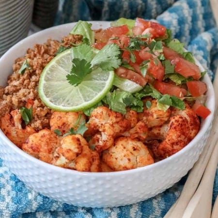 close up of frozen cauliflower and prepped taco meat in a white bowl