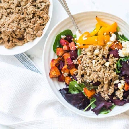 white counter with bowl of cooked ground turkey in the background, seasoned ground turkey as a salad topping in the foreground