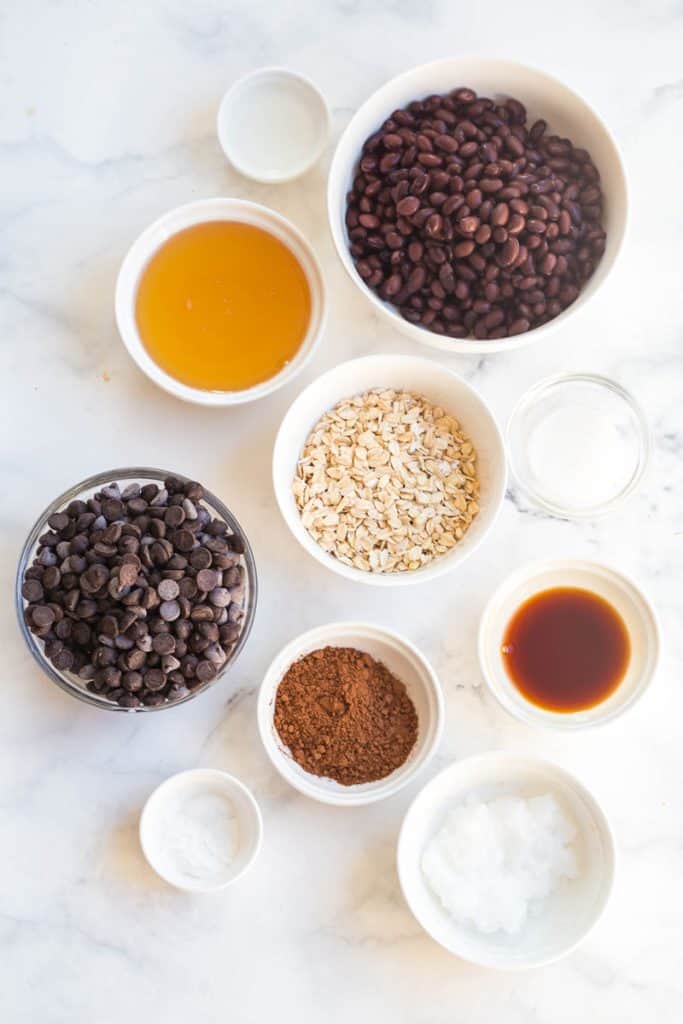 ingredients in these black bean vegan protein brownies, in white bowls on a white countertop