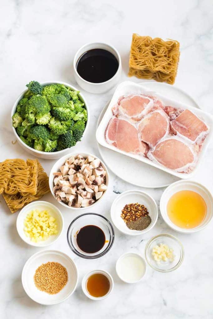 on a white counter, ingredients for this recipe are poured into white bowls. Chicken is in a white container.