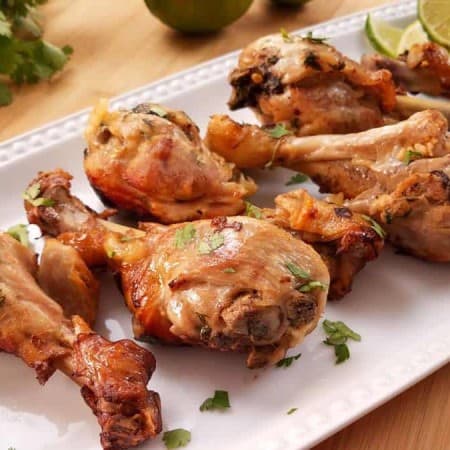 cooked chicken drumsticks on a white rectangular plate