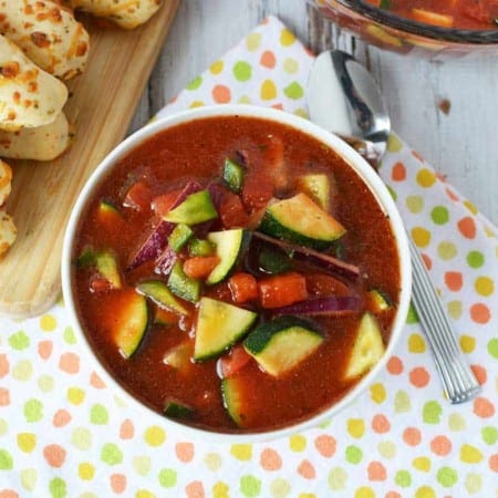 gazpacho soup in white bowl with breadsticks