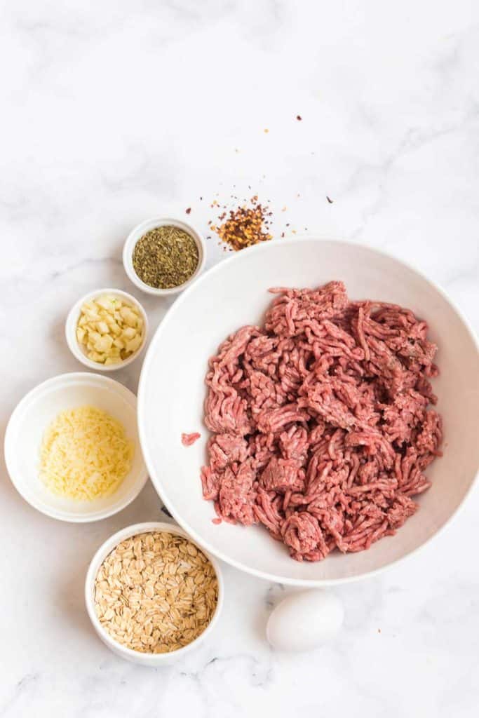 ingredients for homemade meatballs in white bowls