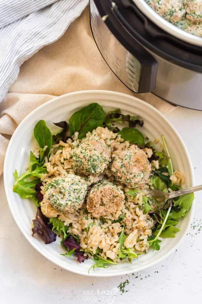 white bowl with spring mix, rice, and turkey swedish meatballs next to instant pot