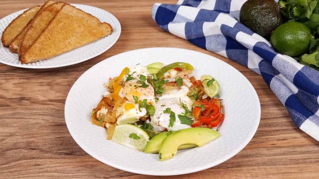 white plate with breakfast fajitas and a plate of toast in the background