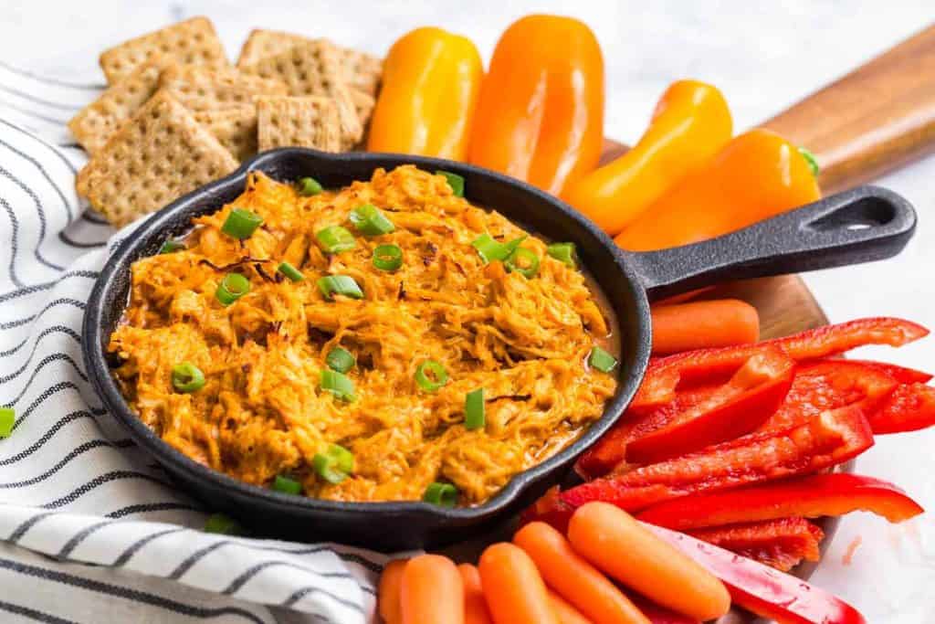 buffalo chicken dip in a skillet surrounded by dipping vegetables and crackers