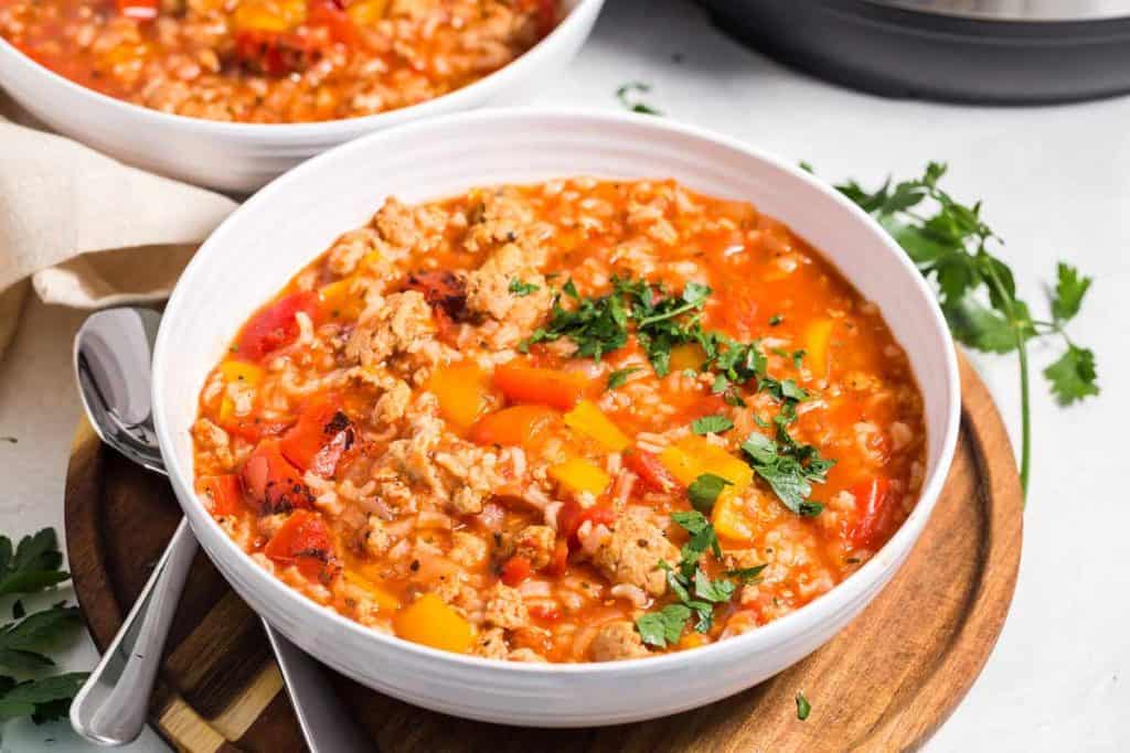 white bowl with stuffed pepper soup on top of a wooded board