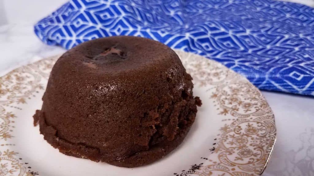 small chocolate cake on a plate with blue towel in background