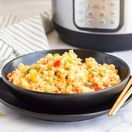 black bowl of Healthy Cauliflower Fried Rice with instant pot in background