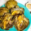 roasted artichoke halves on a turquoise plate