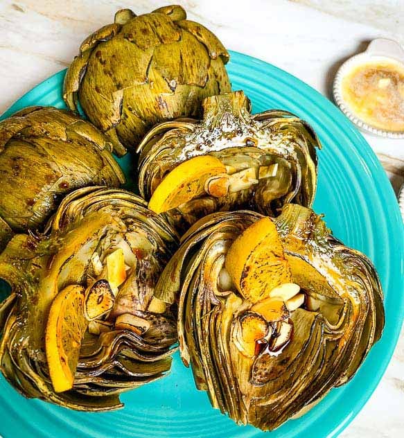 roasted artichoke halves on a turquoise plate