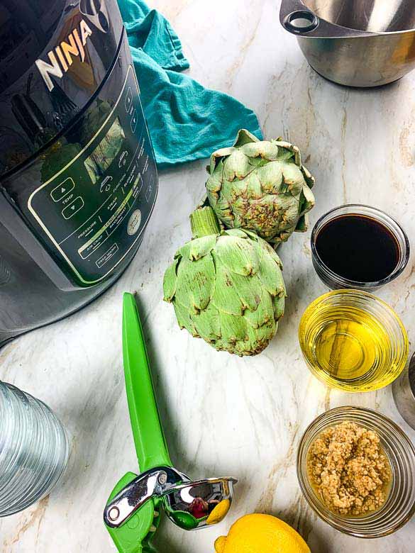 ninja foodi, artichokes, and other ingredients on white countertop