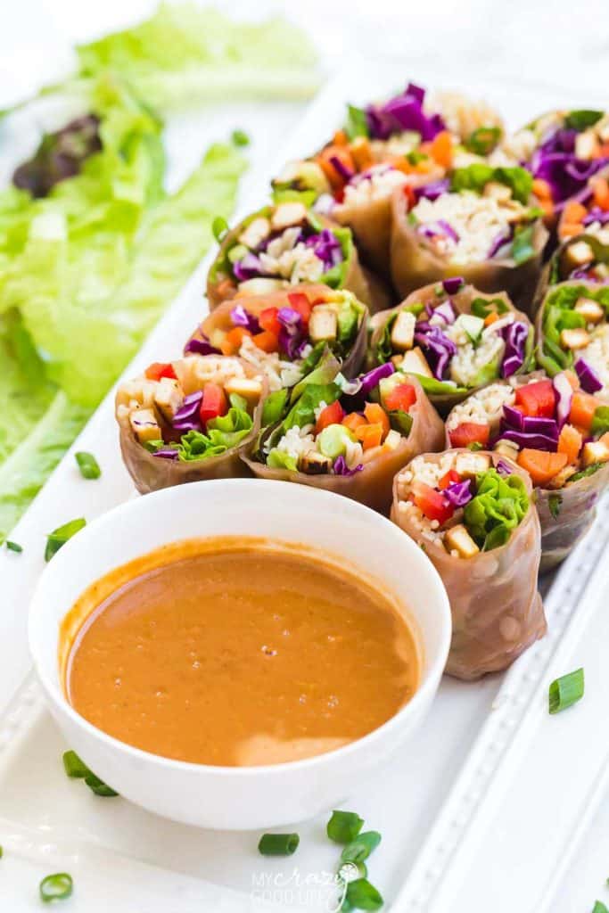 white tray with dish of peanut sauce and veggie egg rolls cut in half