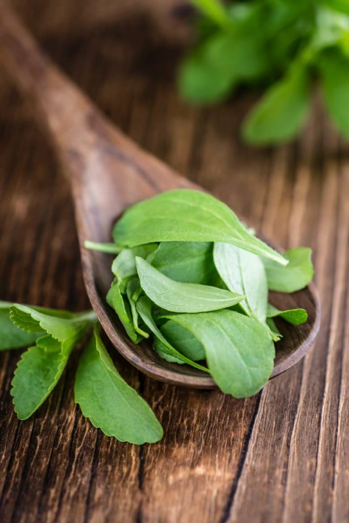 stevia leaves on a wooden spoon