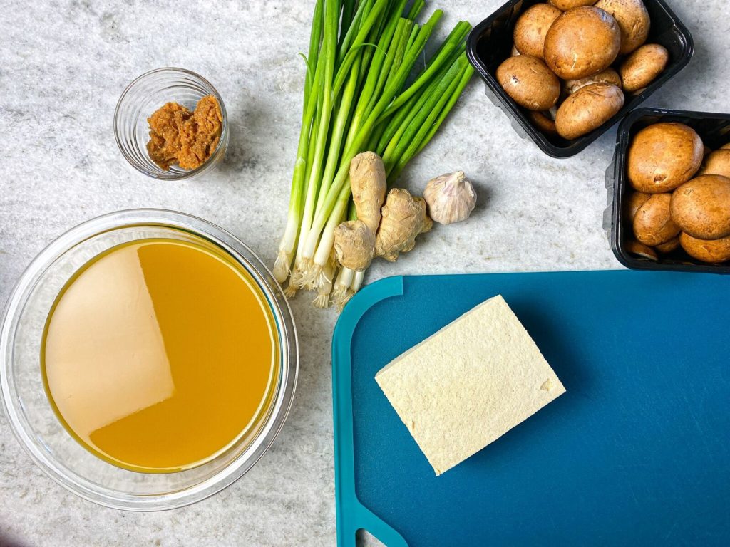 Picture of ingredients for miso soup, broth, green onions, mushrooms, and miso paste.