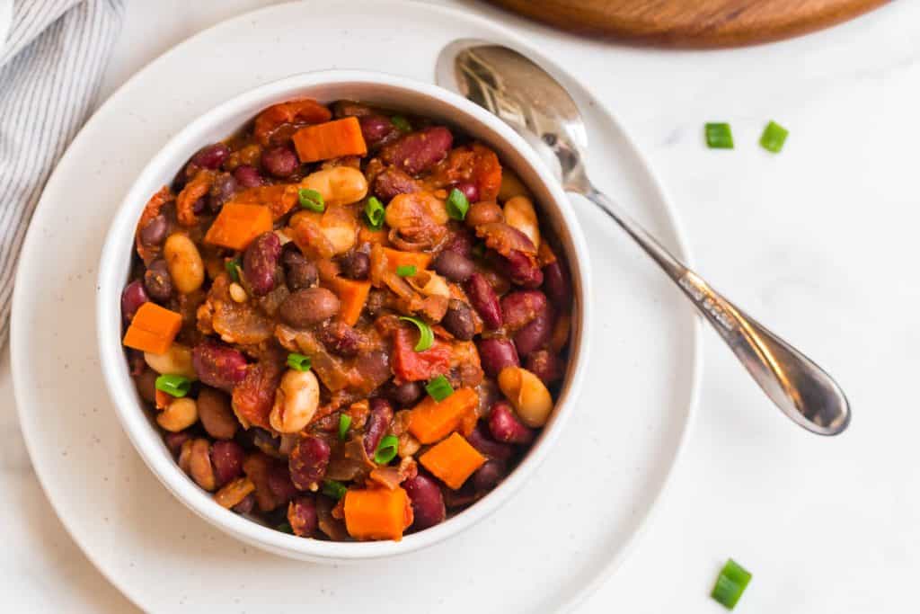 top down picture of vegan chili in a white bowl with a soup on the plate next to it