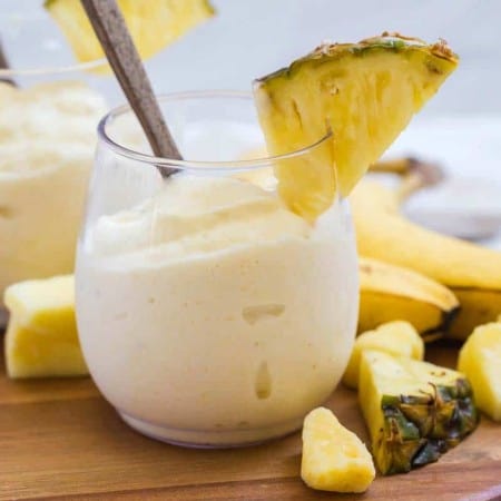 two dole whips in clear glass with pineapple garnish on the cup and around the base